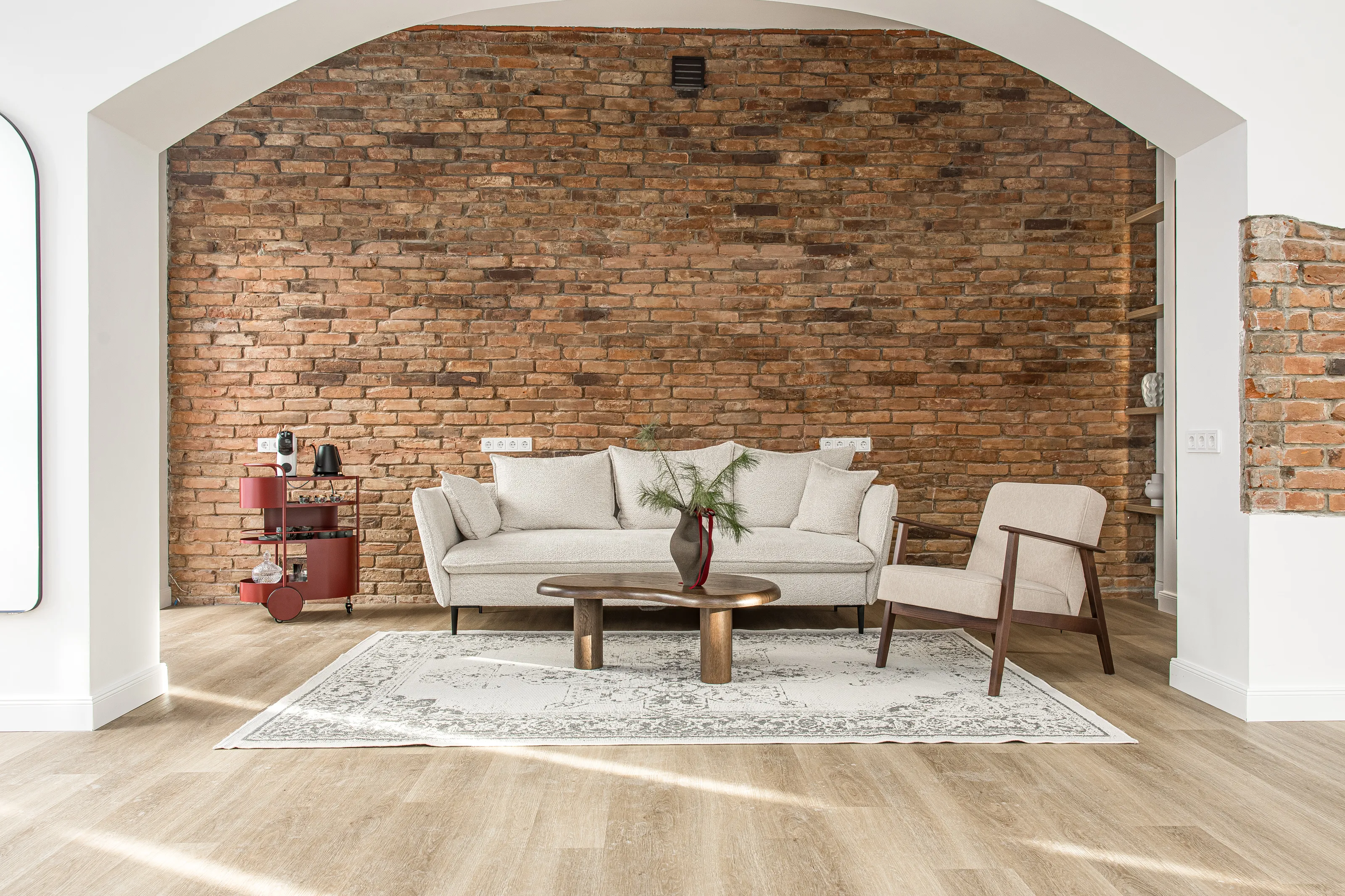 Jaukus poilsio kampelis su sofa prie raudonų plytų sienos ir arka